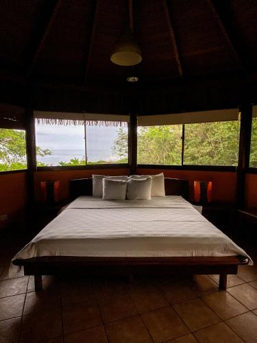 a large bed in a room with windows at Hotel Vista de Olas in Santa Teresa Beach