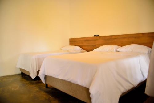 two beds in a room with white sheets at ORIGEN FINCA HOTEL in Quimbaya