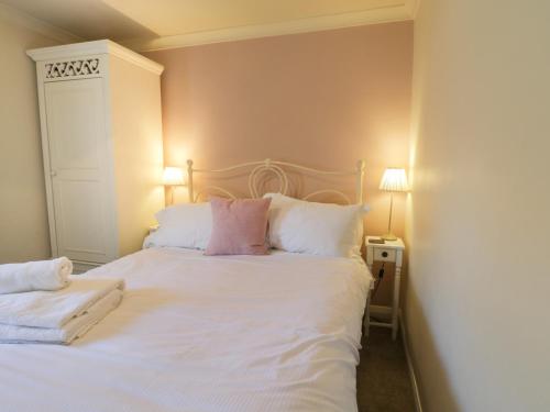 a bedroom with a white bed with two pillows at Cosy Cottage in Potto