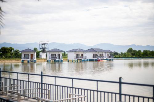 a group of houses on the water with mountains in the background at Lumbini Palace Resort in Lumbini