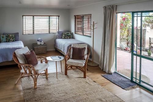 a bedroom with a bed and two chairs and a table at La Dolce Vita Whangamata in Whangamata