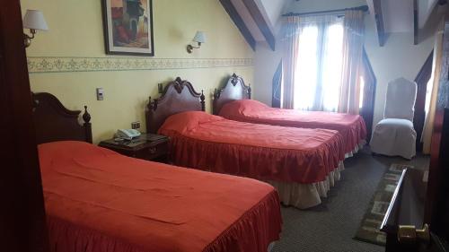 two beds in a hotel room with red sheets at Hostal Paola in Sucre