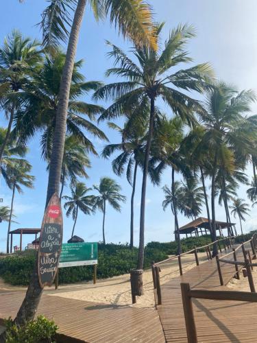 a boardwalk with palm trees on a beach at Costa do Sauipe Casa dentro do complexo hoteleiro in Costa do Sauipe