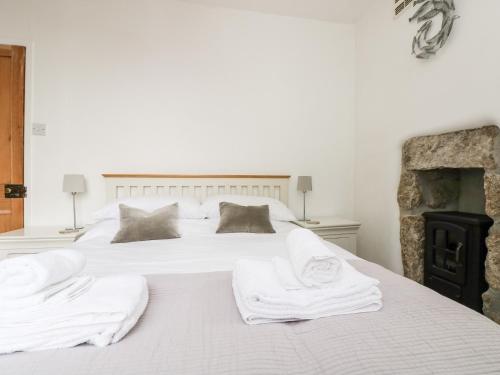 a bedroom with a white bed with towels on it at Mole Cottage in Mousehole