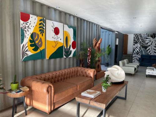 a living room with a brown couch and paintings on the wall at Campo Abierto in Rivera
