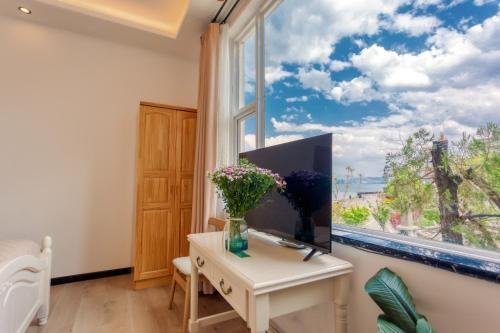a room with a window with a desk and a table with flowers at Blue Sea Hotel in Dali