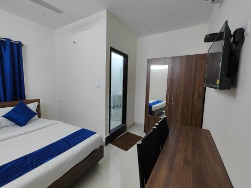 a bedroom with a bed and a tv and a table at The Jugglers Rest in Mysore
