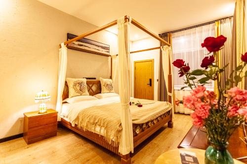 a bedroom with a canopy bed and a vase of flowers at Blue Sea Hotel in Dali