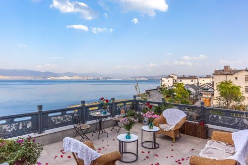 een balkon met tafels en stoelen en uitzicht op het water bij Blue Sea Hotel in Dali