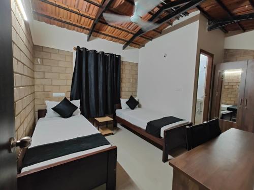 a bedroom with two beds and a desk and a mirror at Minimal Poshtel in Mysore