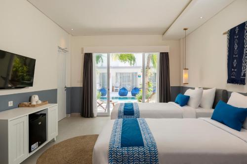 a hotel room with two beds and a television at The Beach House Resort in Gili Trawangan