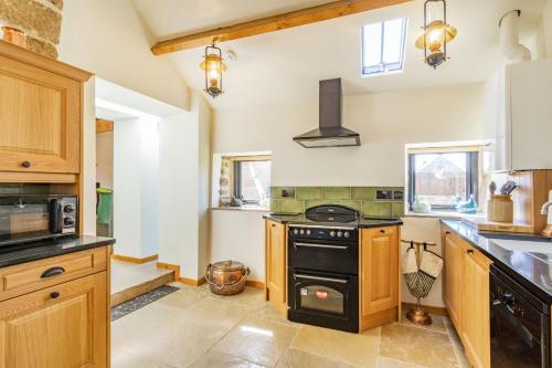 a kitchen with wooden cabinets and a black stove at Basil's Barn in Whitby