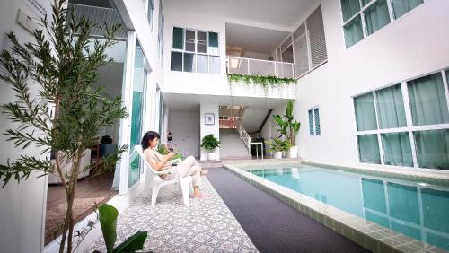 uma mulher sentada numa cadeira ao lado de uma piscina em The Inn10 Pool Villa Pattaya, Entire Villa, 9 Bedrooms, Private Indoor Swimming Pool, ดิ อินน์เท็น em Pattaya Central