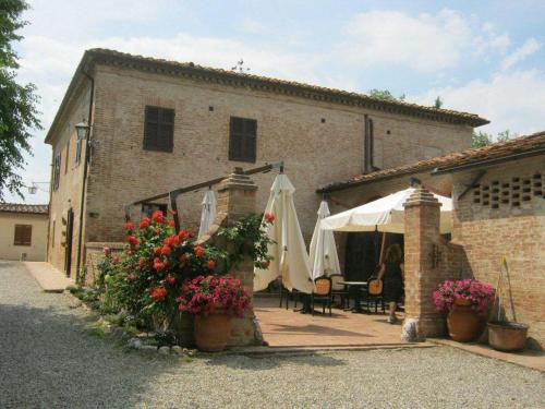 a building with a patio with umbrellas and flowers at Il Canto del Sole in Monteroni dʼArbia