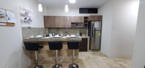 a kitchen with a bar with stools and a refrigerator at NCG SUITE SAMANES in Guayaquil