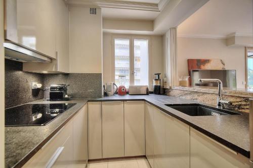 une cuisine avec des armoires blanches et un évier dans l'établissement IMMOGROOM - 2 BR - Air conditioning - Wifi - Terrace - Common parking, à Cannes