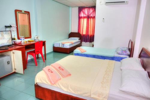 a bedroom with two beds and a desk and a mirror at The Room Concept Homestay in Kuah