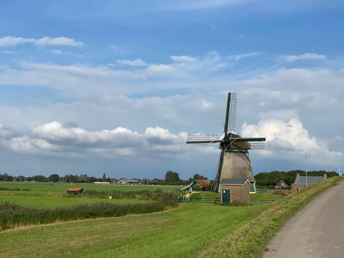 a windmill in a field next to a road at Holidayhome Geuzenhoeve op de Munnickaij in Schellinkhout