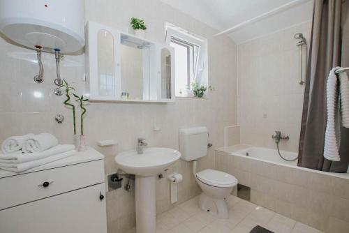 a white bathroom with a sink and a toilet and a tub at Apartman Relax 2 in Zaboric