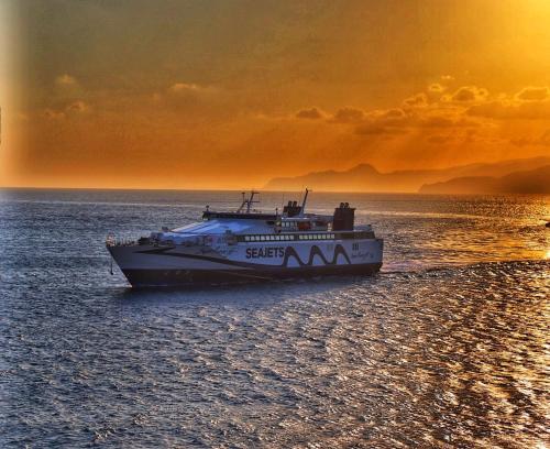 a boat on the water with a sunset in the background at Pergola Hotel in Agios Nikolaos