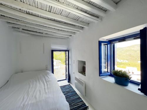 a white bedroom with a bed and a window at Serifos White in Serifos Chora