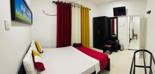 a bedroom with a bed with red and yellow curtains at Funwhales Rest House in Negombo
