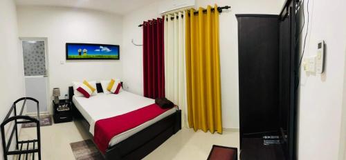 a bedroom with a bed with red and yellow curtains at Funwhales Rest House in Negombo