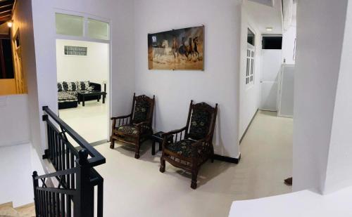 a living room with two chairs and a painting on the wall at Funwhales Rest House in Negombo