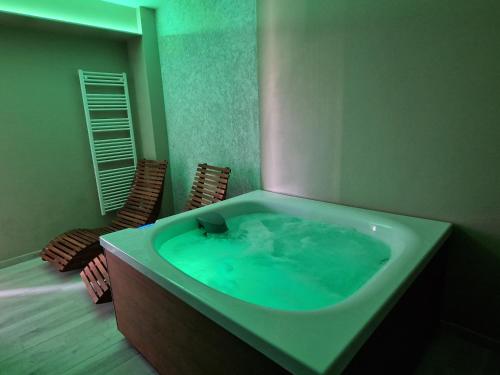 La salle de bains est pourvue d'une grande baignoire avec de l'eau verte. dans l'établissement Accanto Alle Mura Rooms & Relax Spa, à Sirolo
