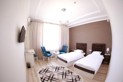 a hotel room with two beds and a table and chairs at Panjakent Plaza in Panjakent