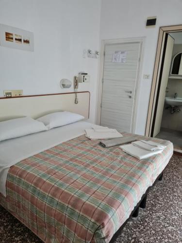 a bedroom with a bed with a plaid blanket at Hotel Marconi Miramare in Rimini