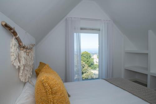 a white bedroom with a bed and a window at Cedros Nature House in Sintra