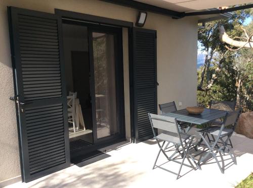 d'une terrasse avec des portes noires, une table et des chaises. dans l'établissement COQUET APPARTEMENT INDÉPENDANT DANS VILLA ENTRE MER ET MONTAGNE, à Sotta