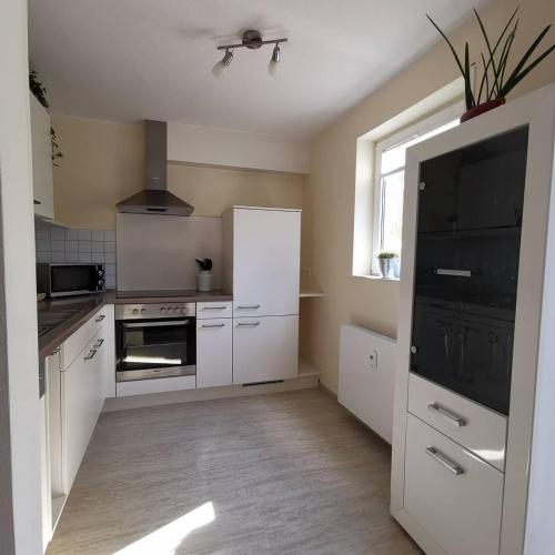 eine Küche mit weißen Schränken und einem schwarzen Kühlschrank in der Unterkunft Ferienwohnung Subat in Ettenheim