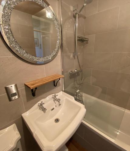 a bathroom with a sink and a mirror and a tub at SANDYVIEWS in Grange Over Sands