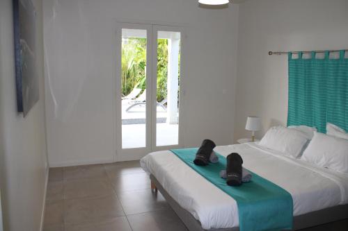 een slaapkamer met een bed met schoenen erop bij Villa Écrin de Nature in Sainte-Rose