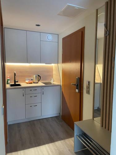 cocina con armarios blancos y puerta de madera en Alintoma Holiday apartment en Palanga