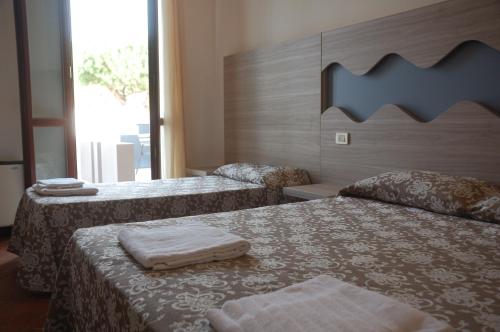 una camera d'albergo con due letti e asciugamani di Hotel Villa Robinia a Casal Borsetti