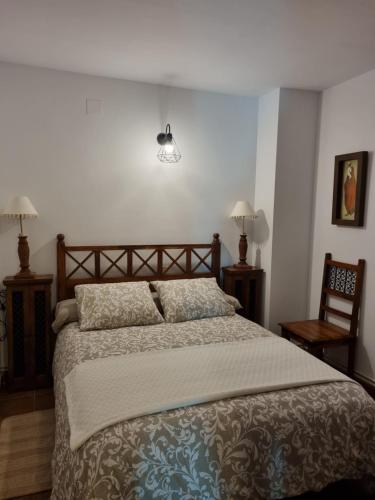 een slaapkamer met een bed en 2 lampen en een stoel bij Casa Mari in Palomera