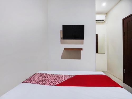 SUPER OYO 91049 D'lima Guest House Sub في Medokanayu: غرفة نوم بيضاء مع سرير وبطانية حمراء