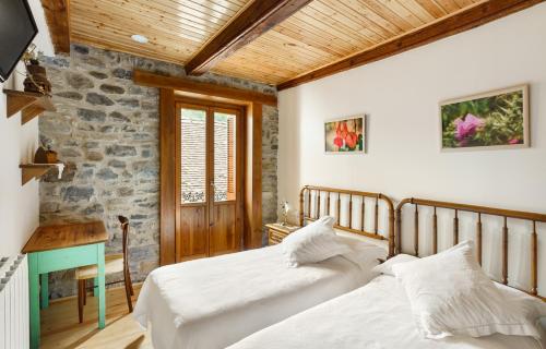 a bedroom with two beds and a stone wall at Casa Rural Francisco Mayo in Isaba