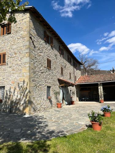 un gran edificio de piedra con plantas delante de él en IL CASALE di ROLANDO, en Castiglione di Garfagnana