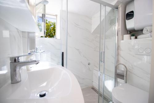 a white bathroom with a sink and a shower at Guest House Steel in Dubrovnik