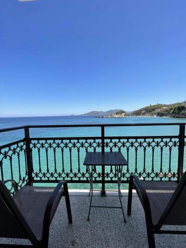 uma mesa e 2 cadeiras numa varanda com vista para o oceano em Maria's room em Samos