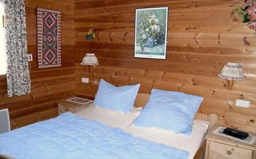 ein Schlafzimmer mit einem Bett und blauen Kissen in der Unterkunft Ferienhaus Nr 5, Typ A, Feriendorf Jägerpark, Bayerischer Wald in Viechtach