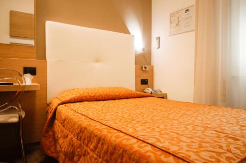 a bedroom with a bed with an orange blanket at Hotel Europa in Desenzano del Garda