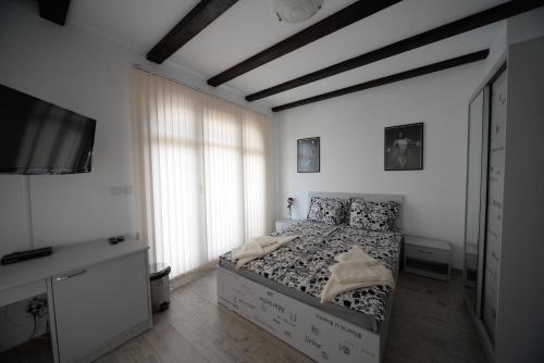 a bedroom with a bed and a flat screen tv at Къща за гости АЛЛА in Byala