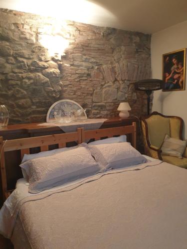 a bedroom with a bed and a stone wall at Helga's House- Una Finestra sul Borgo in Ambra
