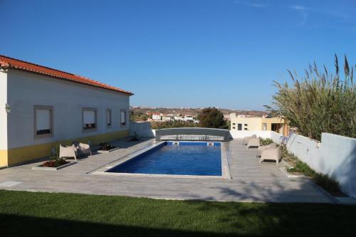 a swimming pool in a yard next to a house at Villa da Bica in Lourinhã