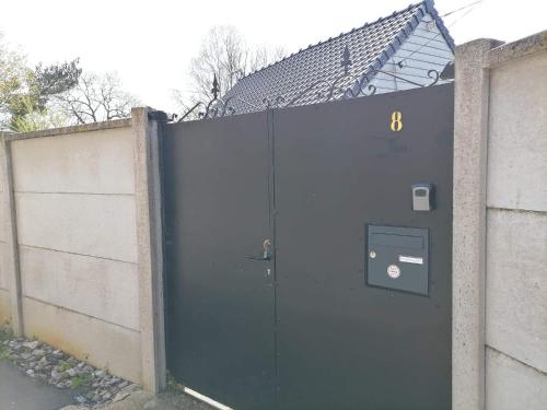 une grande porte grise avec un panneau à côté d'une clôture dans l'établissement Le pied à terre, à Feuquières-en-Vimeu